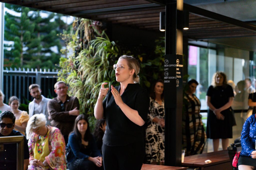 A lady standing delivering Auslan to crowd